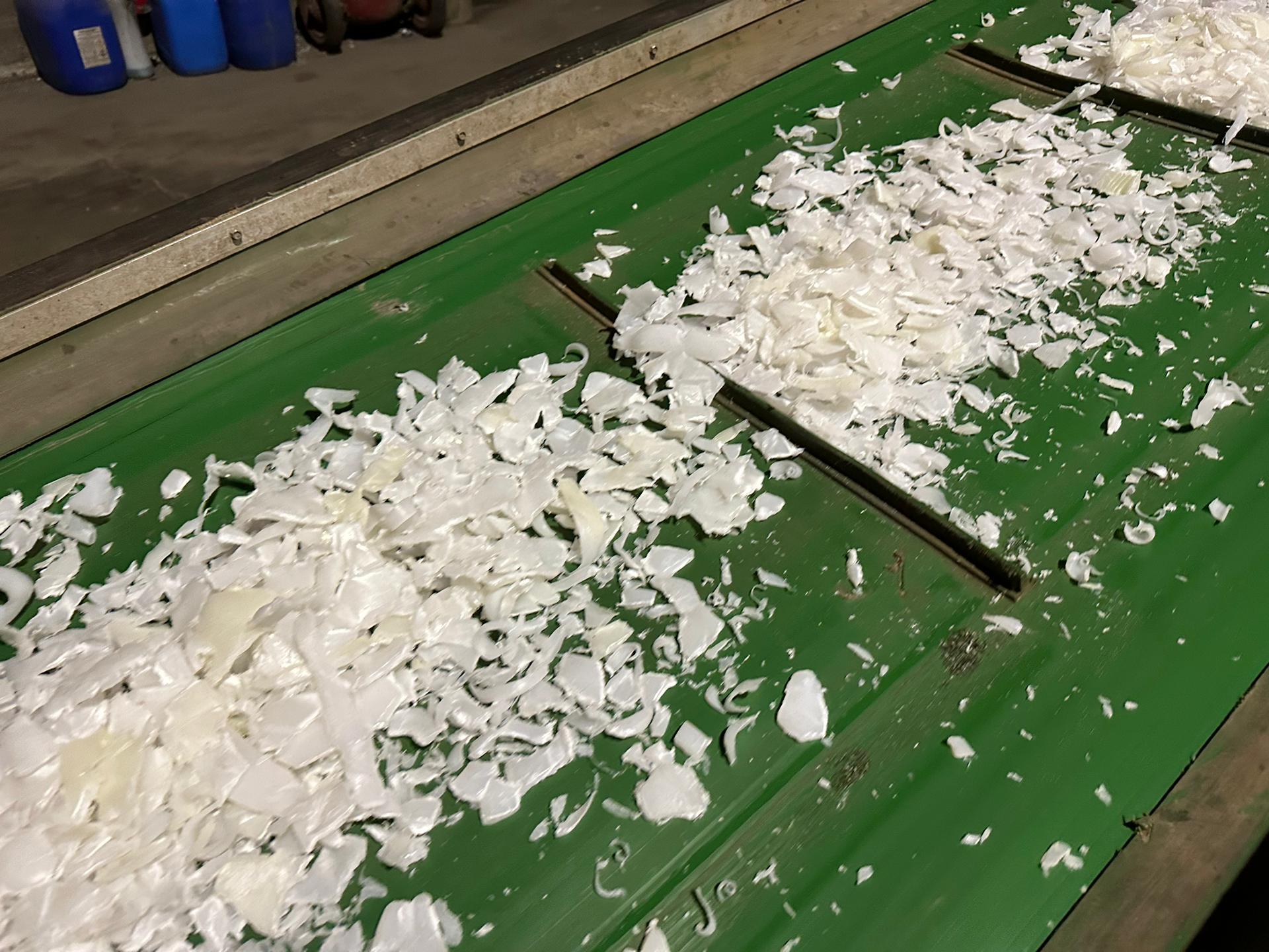 Shredded plastic from recycled IBCs on a conveyor belt